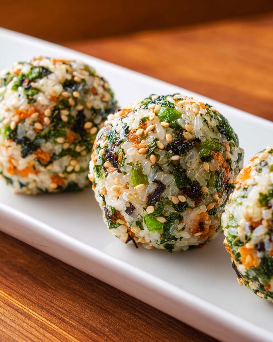 Three round rice balls sit in a row on a long white plate. Each ball is made of white rice mixed with small green seaweed pieces, orange carrot bits, and scattered tan sesame seeds, giving a textured and colorful look. The balls have a slightly rough surface due to the mixed ingredients, and the background is a warm wooden surface. The photo has a close-up view showing the details and textures clearly. photo taken with an iphone --ar 4:5 --v 7