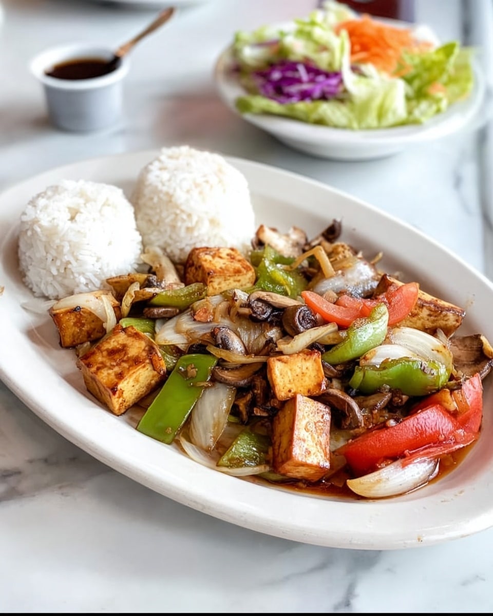 A white oval plate holds a colorful stir-fry dish with two small mounds of white rice placed at the back. The stir-fry has visible large chunks of golden-brown tofu mixed with sautéed vegetables, including green bell peppers, sliced white onions, light brown mushrooms, and bright red tomato pieces, all coated lightly with sauce. The plate is on a surface with a white marbled texture. In the background, there is a white bowl with a light salad of lettuce, purple cabbage, and shredded carrots, and a small cup with dark sauce. Photo taken with an iphone --ar 4:5 --v 7