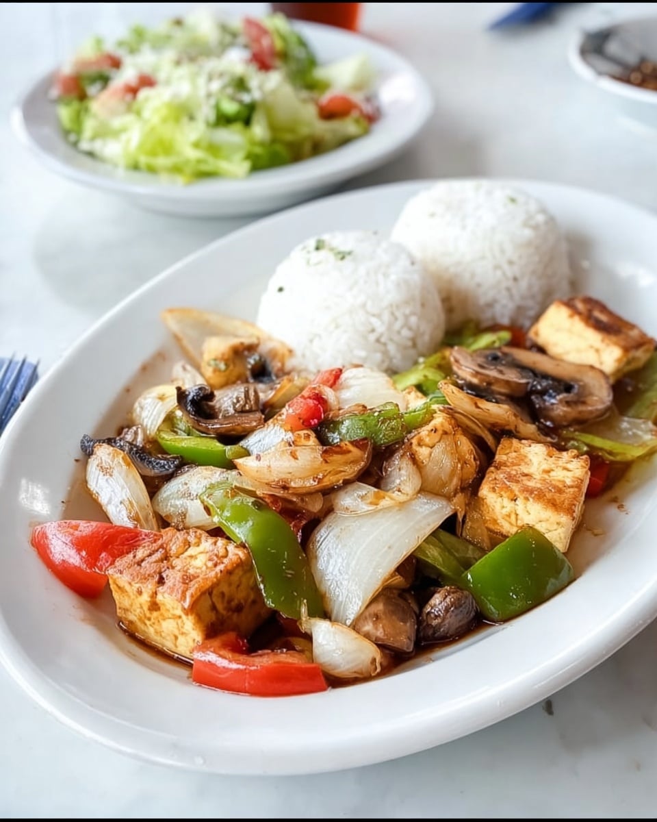 The dish shows a white oval plate with two neat white rice balls at the back. In front of the rice, there is a colorful mix of cooked vegetables and tofu cubes. The vegetables include sliced onions, mushrooms, green bell peppers, and red tomato pieces, all lightly glazed with a shiny sauce. The tofu cubes are golden brown on the outside. Each vegetable and tofu piece is clearly visible, giving a fresh look. In the background, a white bowl filled with light green salad and some dressing on top can be seen, all set on a white marbled surface. Photo taken with an iphone --ar 4:5 --v 7
