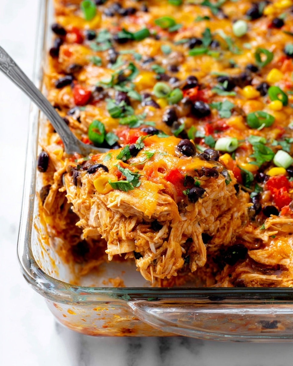The image shows a close-up view of a layered casserole dish in a glass baking tray with a spoon scooping a portion. The dish has multiple layers including shredded cooked chicken mixed with melted cheese, black beans, red bell peppers, and yellow corn kernels. Fresh chopped green herbs and sliced green onions are sprinkled on top, adding a bright green color contrast to the warm orange, red, and black tones. The texture looks creamy and cheesy with visible grainy beans and soft chicken pieces. The baking tray sits on a white marbled surface. photo taken with an iphone --ar 4:5 --v 7