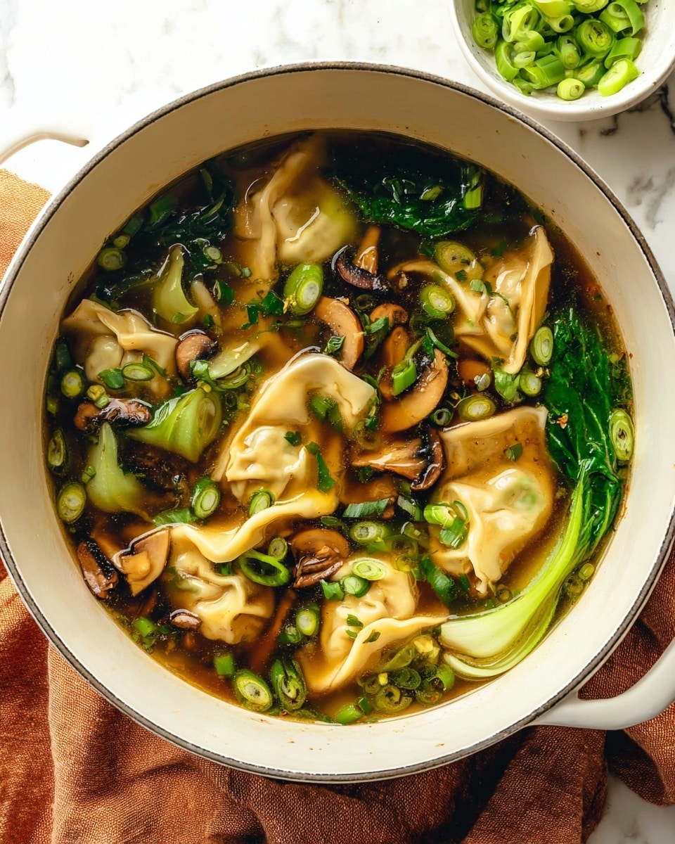 A close-up view of a white bowl filled with clear brown broth soup that has seven light cream-colored wontons floating on top. The wontons are folded with soft, smooth texture and slight translucence. Small pieces of diced orange carrots and green herbs with leafy texture are mixed in the broth, adding color contrast. The bowl has a thin dark rim and sits on a white marbled surface. photo taken with an iphone --ar 4:5 --v 7