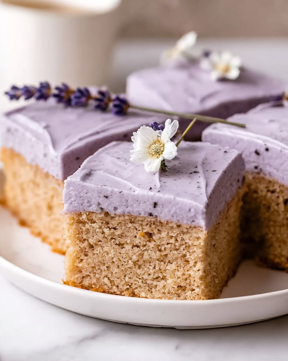 The image shows a close-up of six square cake slices arranged neatly on a white plate placed on a white marbled surface. Each slice has two layers: the bottom layer is a dense, light brown cake with a slightly crumbly texture, and the top layer is a thick, smooth lavender-colored frosting with small dark specks. One slice in the front is cut with a clean edge, revealing the inside of the cake, and it is decorated on top with a small white flower and a sprig of tiny lavender flowers. Photo taken with an iphone --ar 4:5 --v 7