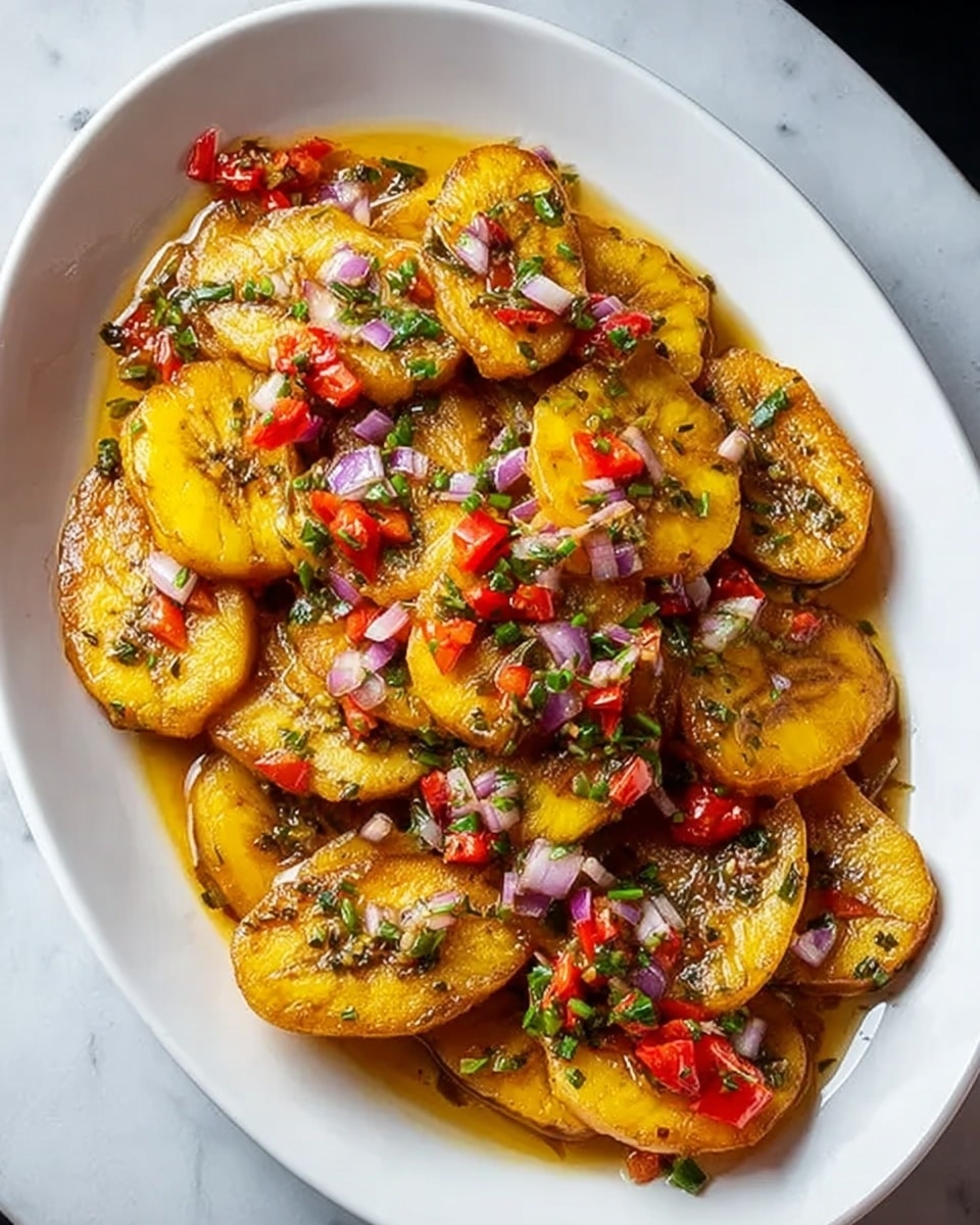 A white oval plate filled with roughly two layers of golden yellow fried plantain slices, each piece slightly browned on the edges, coated in a glossy sauce. On top are scattered small pieces of red bell pepper, diced pale purple onions, and finely chopped green herbs, adding bright splashes of color and texture. The sauce appears oily and shiny, pooling gently around the plantains, reflecting light. The background is a white marbled surface. photo taken with an iphone --ar 4:5 --v 7