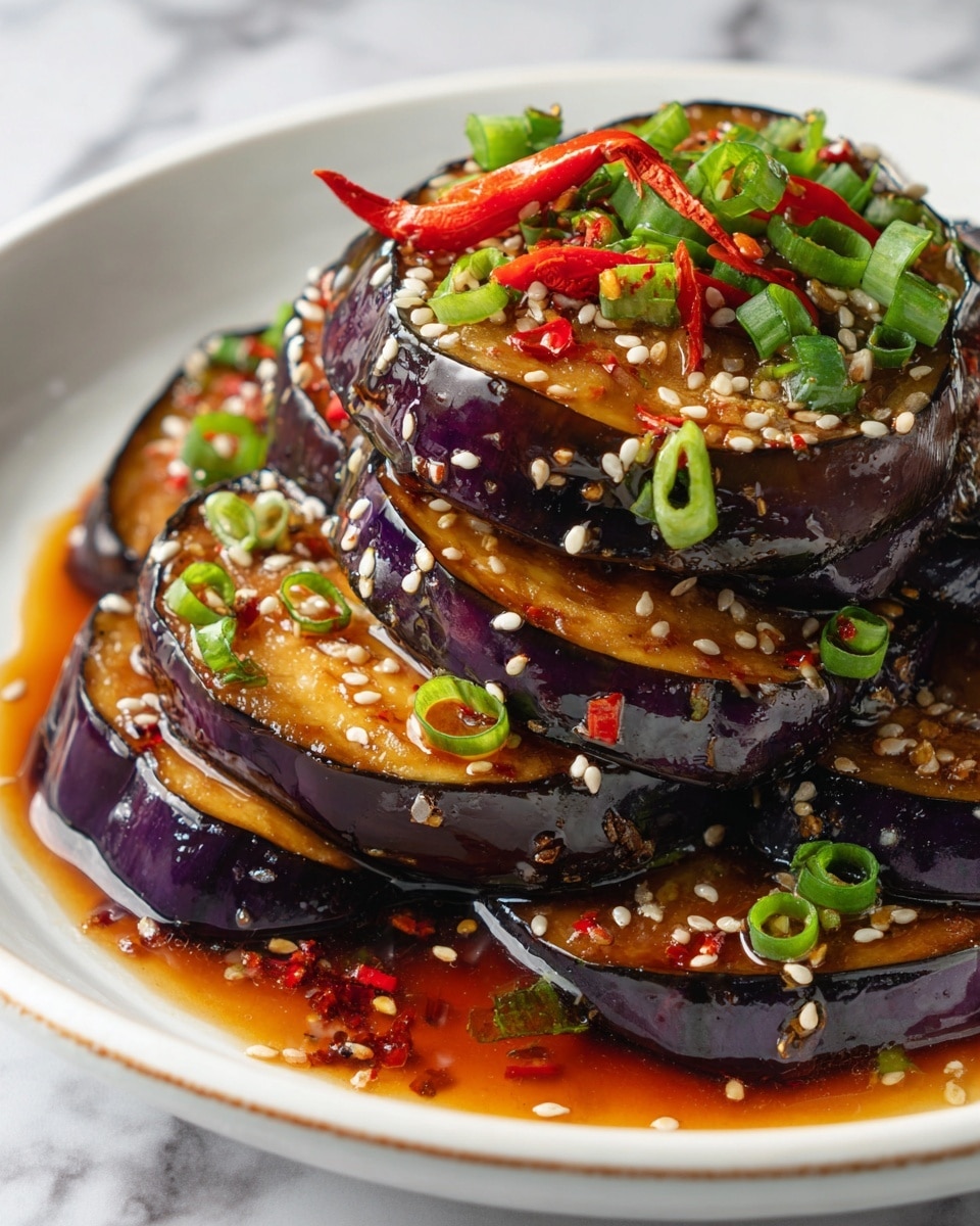 The dish shows about ten rectangular pieces of cooked eggplant stacked in two layers on a white plate. The eggplant has a dark purple skin with a glossy, caramel-brown cooked surface that looks tender and slightly shiny from sauce. The top layer is sprinkled with sesame seeds, chopped green onions, and small bits of red chili, adding green and red color contrast on the brown and purple eggplant. The sauce pools slightly around the base of the stack on the plate. The plate sits on a white marbled texture. photo taken with an iphone --ar 4:5 --v 7