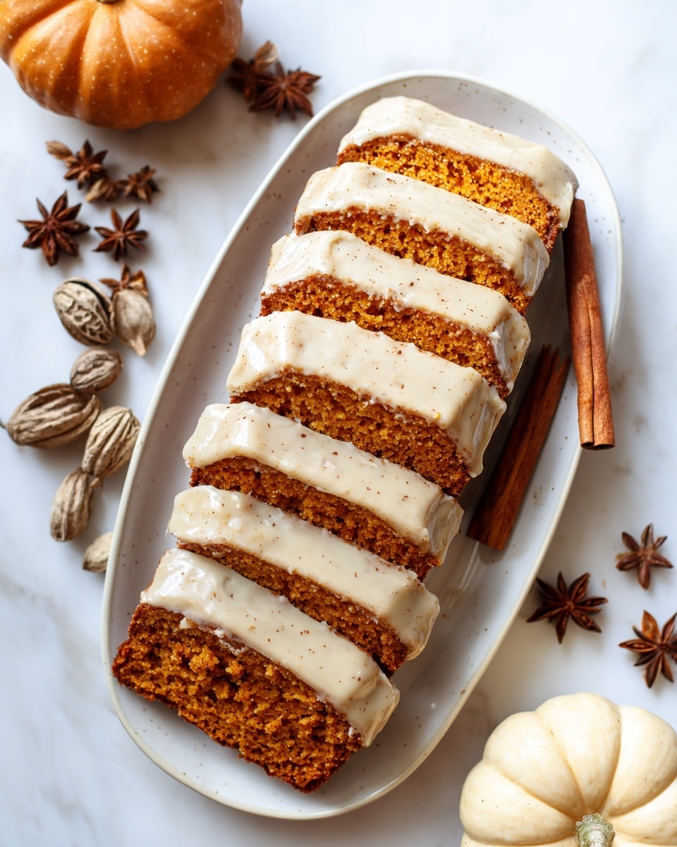 A loaf of pumpkin bread is sliced into seven pieces and placed on a white oval plate. The bread is a warm orange color with a moist, dense texture. Each slice is topped with a thick, creamy layer of white icing that has a smooth texture and soft cinnamon specks, dripping slightly down the sides. A cinnamon stick lies parallel next to the bread on the plate. The plate sits on a white marbled surface with soft light highlighting the textures, and part of a small pumpkin is visible on the right edge. photo taken with an iphone --ar 4:5 --v 7