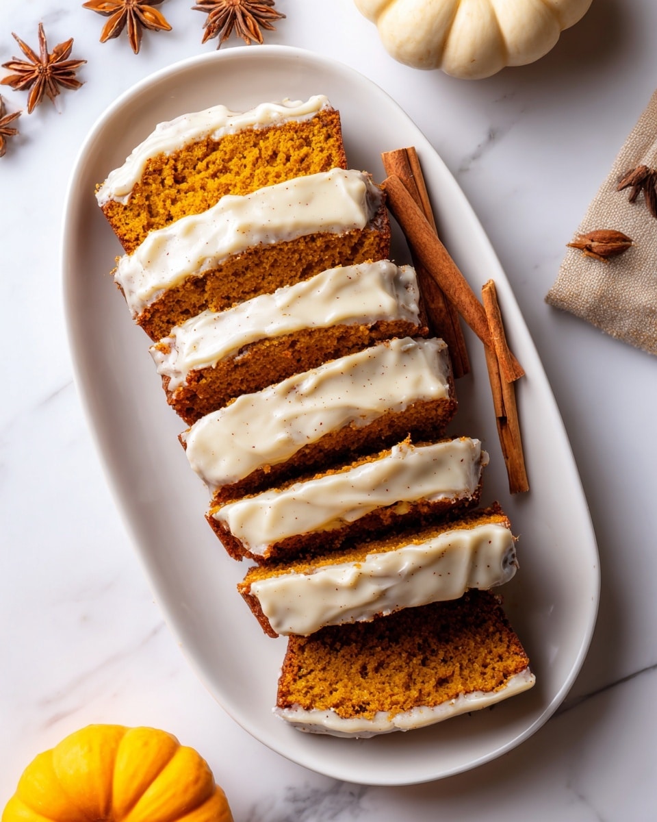 A white oval plate holds a sliced pumpkin loaf cake with seven visible slices. Each slice shows a moist, bright orange inside with a textured crumb, topped with a thick layer of cream-colored icing speckled with cinnamon or spice. The cake slices are arranged in a neat line, slightly overlapping each other from top to bottom. To the right of the cake on the plate is a cinnamon stick. The plate rests on a white marbled surface, surrounded by whole nutmeg, star anise, a cinnamon stick, and a small beige pumpkin on the bottom right. The lighting is bright and soft, highlighting the smooth and creamy texture of the icing. Photo taken with an iphone --ar 4:5 --v 7
