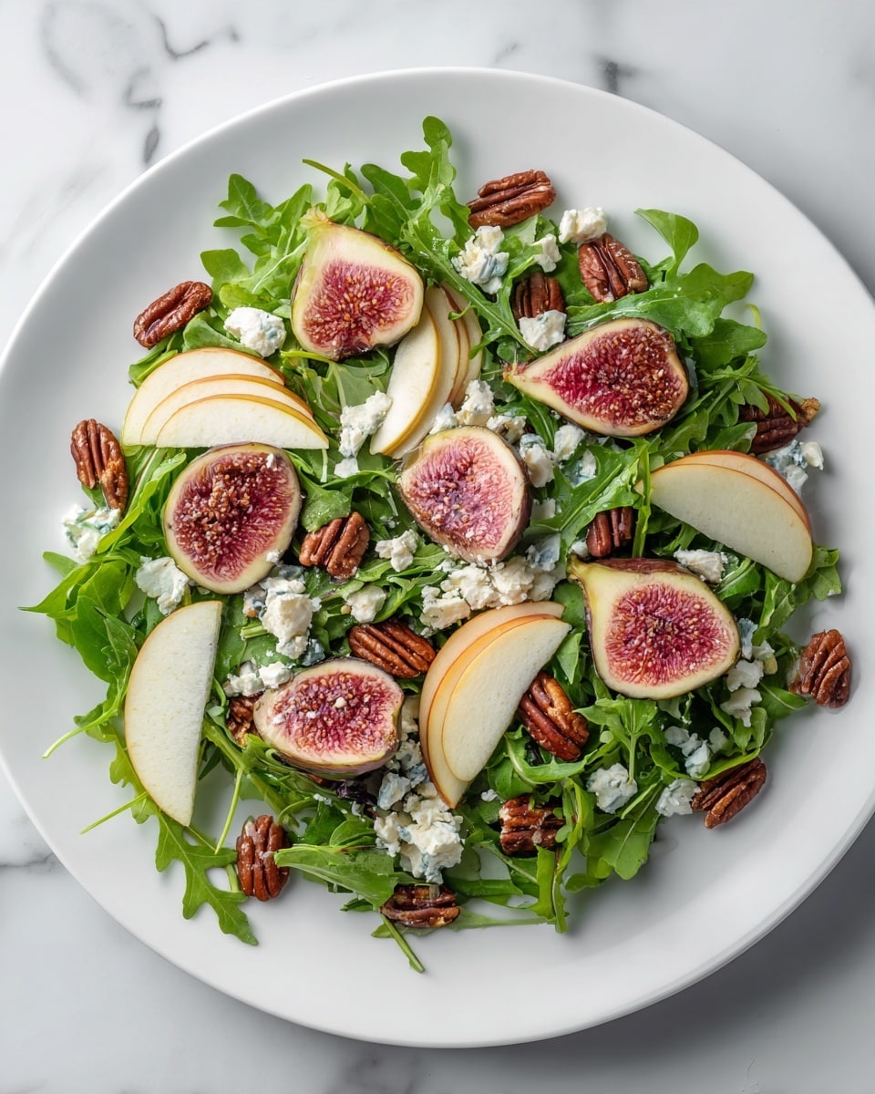 A white plate filled with a fresh green base of arugula leaves, topped with many slices of ripe figs showing pink flesh and seeds inside. Thin slices of red-skinned apple or pear are scattered around, adding light cream and red tones. Small white crumbles of cheese are spread evenly on top, contrasting with the dark brown pecan nuts placed around the salad. The dish looks fresh and colorful with green, pink, white, brown, and red details, all on a white marbled surface. Photo taken with an iphone --ar 4:5 --v 7